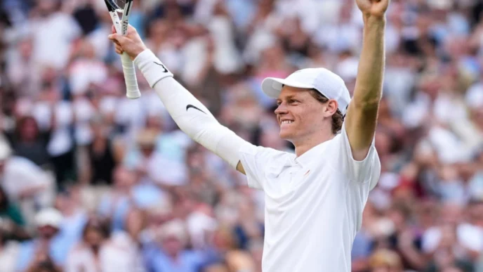 Jannik Sinner celebrates with raised arms after a tennis match victory.
