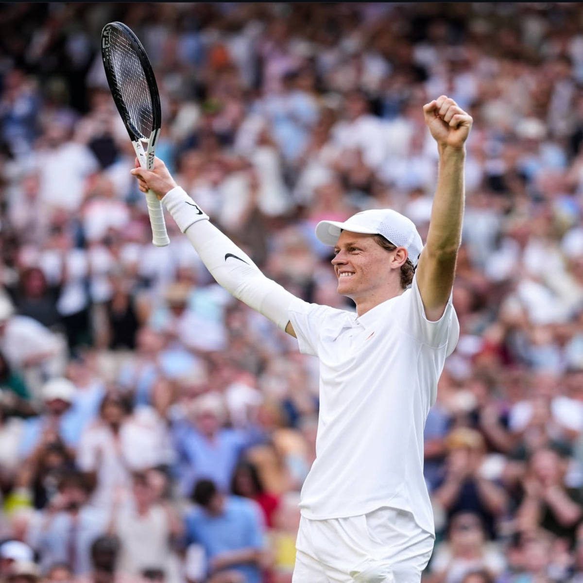 Jannik Sinner celebrates with raised arms after a tennis match victory.