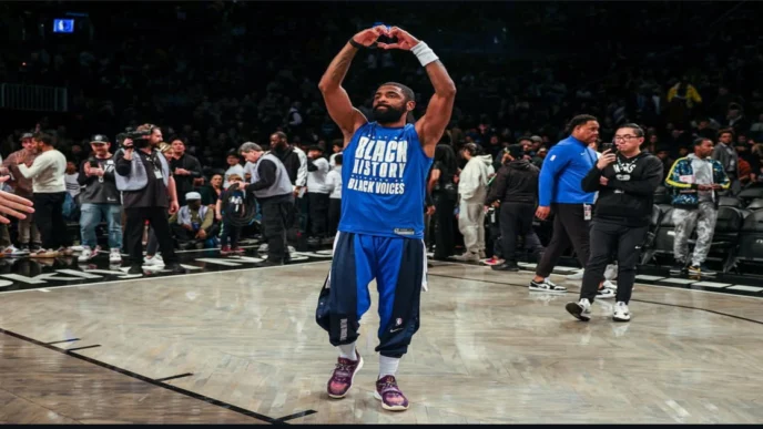 Kyrie Irving makes heart gesture on court wearing “Black History Black Voices” shirt.