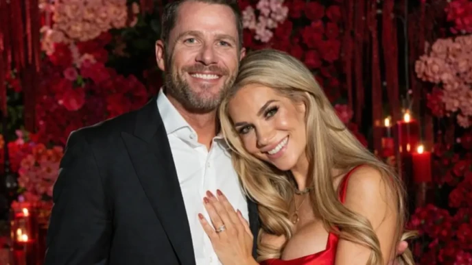Allison Holker smiling in a red satin dress while posing with her partner at a romantic floral event backdrop