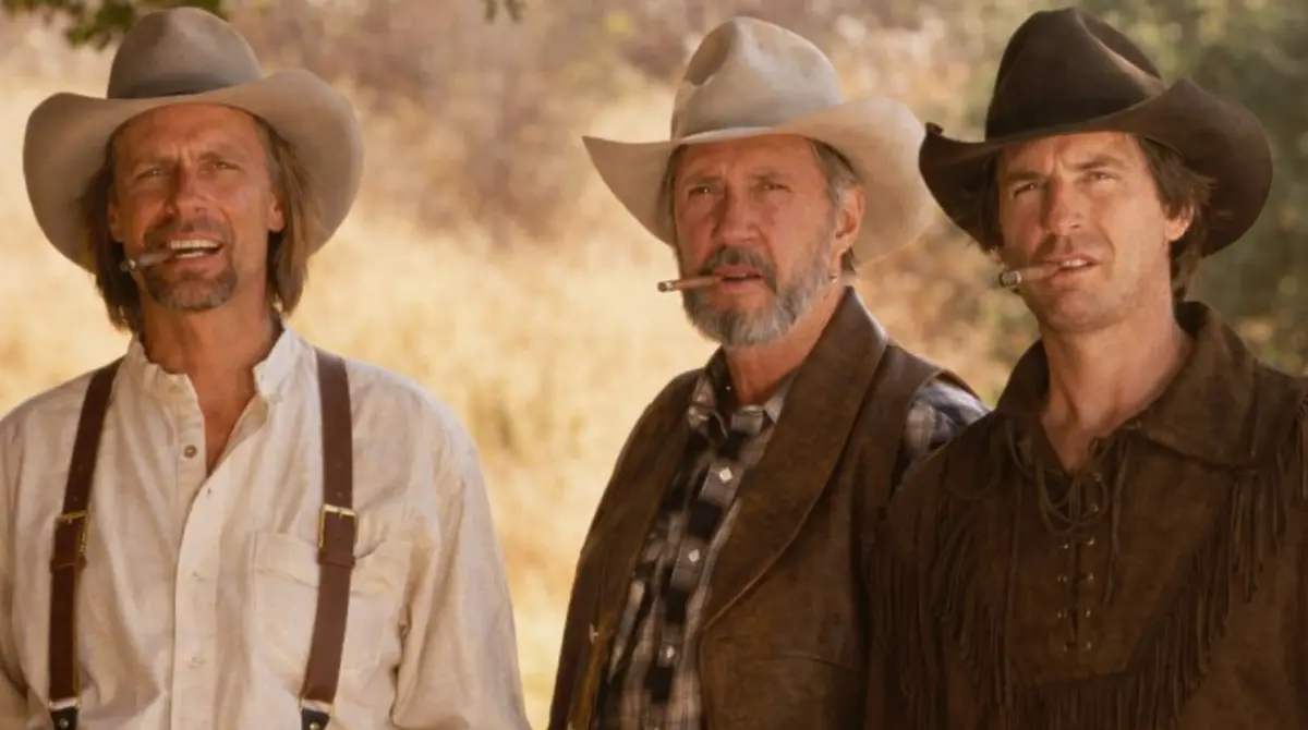 David Carradine standing with two cowboys outdoors in a western-style scene, wearing cowboy hats and holding cigars