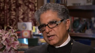 Deepak Chopra speaking during an interview in a warm indoor setting, close-up portrait