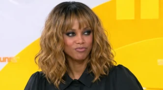 Tyra Banks portrait with wavy blonde-brown hair and black outfit on yellow studio background