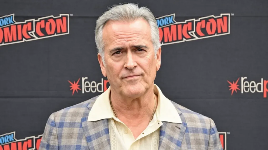 Bruce Campbell posing for a portrait at New York Comic Con in a plaid blazer