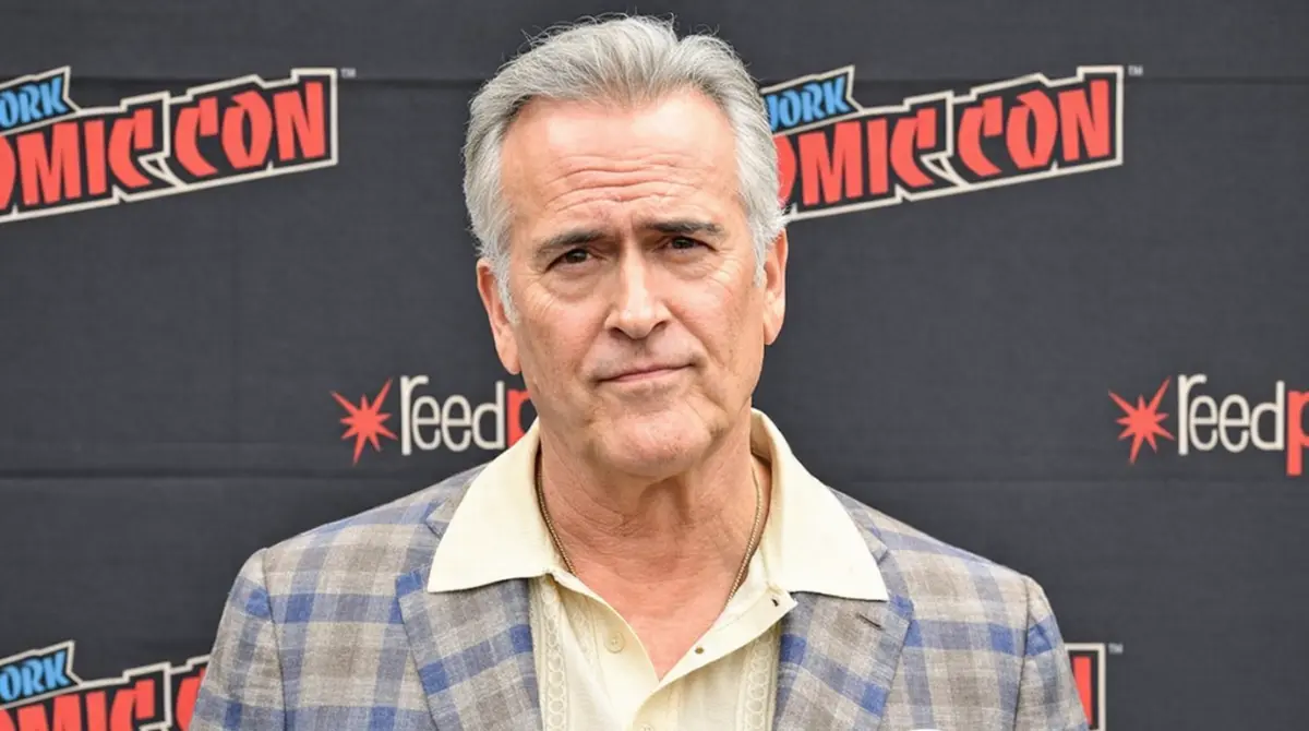 Bruce Campbell posing for a portrait at New York Comic Con in a plaid blazer