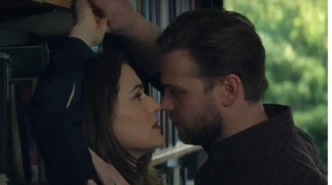 Close-up library scene from Vladimir showing two characters in an intense face-to-face moment near a bookshelf.