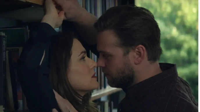 Close-up library scene from Vladimir showing two characters in an intense face-to-face moment near a bookshelf.
